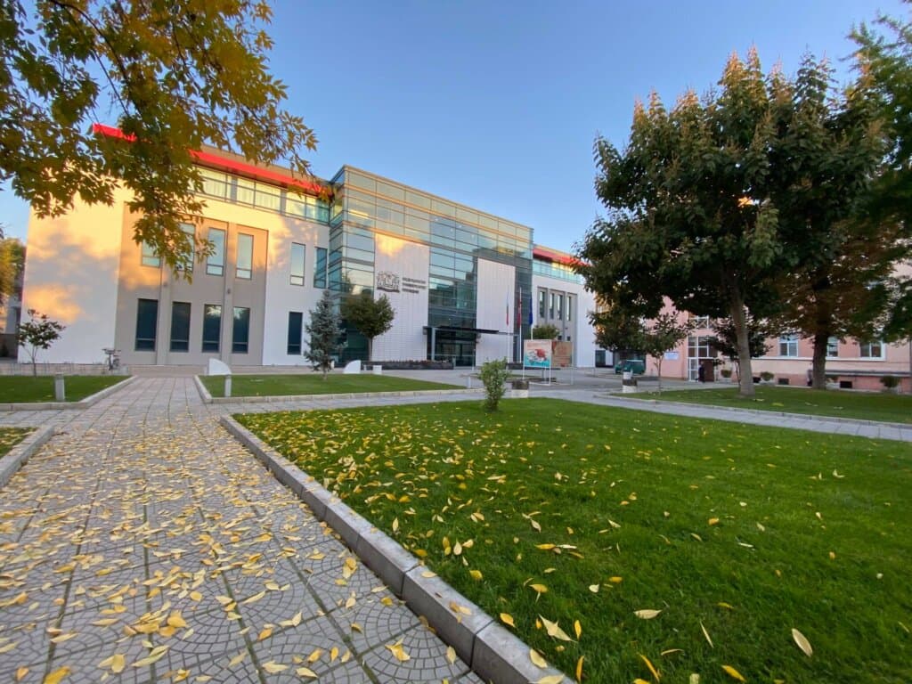 A Medical University – Plovdiv campus building, with the university's entrance sign and the Bulgarian flag